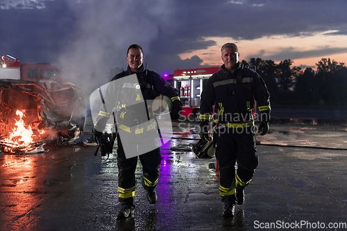 Image of Brave Firefighters Team Walking to the Camera. In Background Paramedics and Firemen Rescue Team Fight Fire in Car Accident, Insurance and Save Peoples Lives concept.