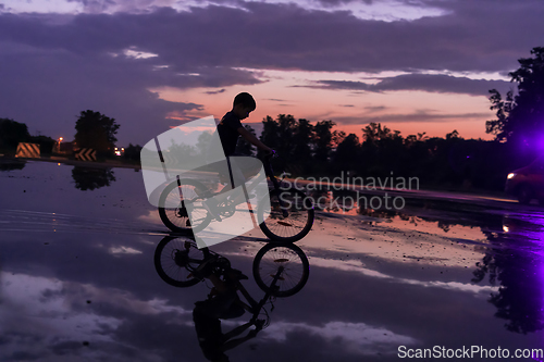 Image of Lonely children silhouette on bike, boy riding bicycle on reflective water. Background beautiful sunset.