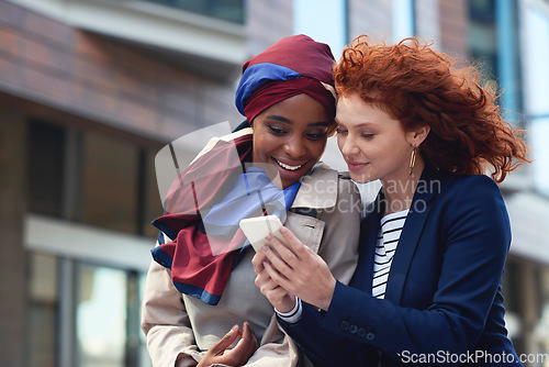 Image of Business women, phone and city travel with diversity while online for communication, gossip or news. Friends reading email on smartphone with 5g network or internet connection outdoor on urban street