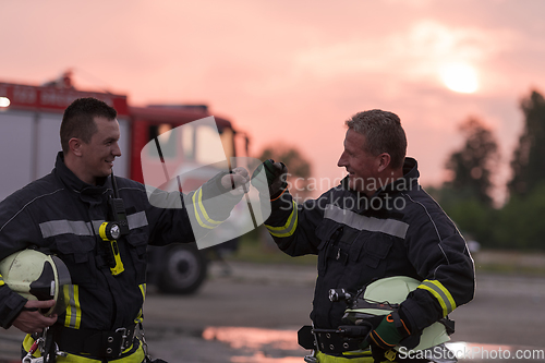 Image of Fireman using walkie talkie at car traffic rescue action fire truck and fireman's team in background.