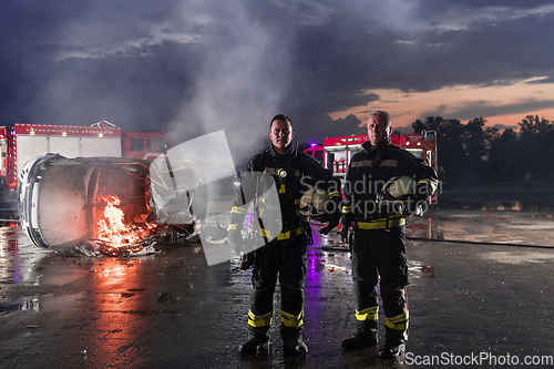 Image of Brave Firefighters Team Walking to the Camera. In Background Paramedics and Firemen Rescue Team Fight Fire in Car Accident, Insurance and Save Peoples Lives concept.