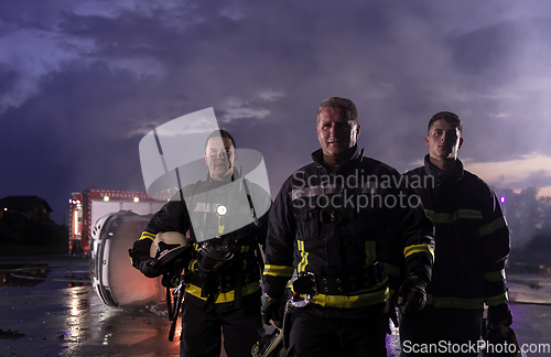 Image of Brave Firefighters Team Walking to the Camera. In Background Paramedics and Firemen Rescue Team Fight Fire in Car Accident, Insurance and Save Peoples Lives concept.