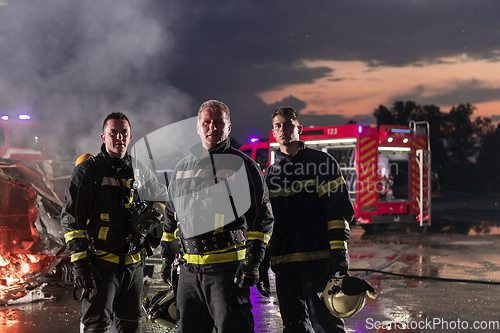 Image of Brave Firefighters Team Walking to the Camera. In Background Paramedics and Firemen Rescue Team Fight Fire in Car Accident, Insurance and Save Peoples Lives concept.