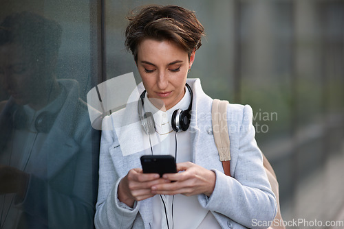 Image of Woman, phone and social media with communication outdoor, chat or email with headphones, travel to work and mockup space. Young creative in city, mobile app with technology and 5g network in Boston