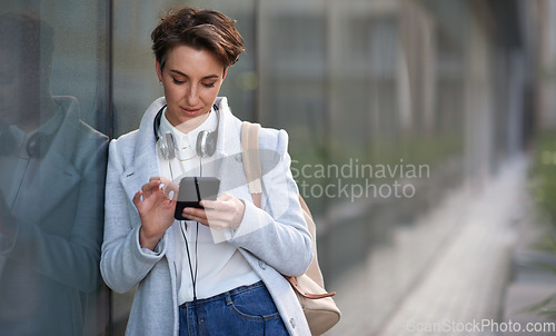 Image of Woman, smartphone and social media with communication outdoor, chat or email with headphones, travel to work and mockup space. Young creative in city, mobile app with technology and 5g in Boston