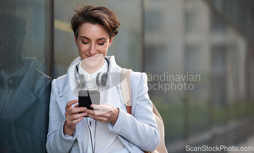 Image of Woman, smartphone and social media with communication in city, chat or email with headphones, travel to work and mockup space. Young creative outdoor, smile at online post with technology in Boston