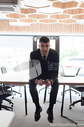 Image of A businessman sitting on his desk, taking a moment to rest and unwind from a demanding workday, displaying a sense of tranquility and relaxation amidst the corporate environment