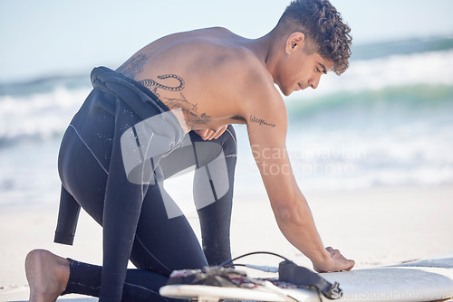 Image of Fitness, beach and surfboard waxing of a man surfer ready for exercise, sport and training outdoor. Waves, ocean and summer workout of a young person with sport equipment in nature for surfing