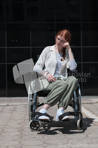 Image of In front of a modern corporate building, a young woman sitting in a wheelchair confidently, symbolizing empowerment, inclusivity, and the strength to overcome challenges in the business world