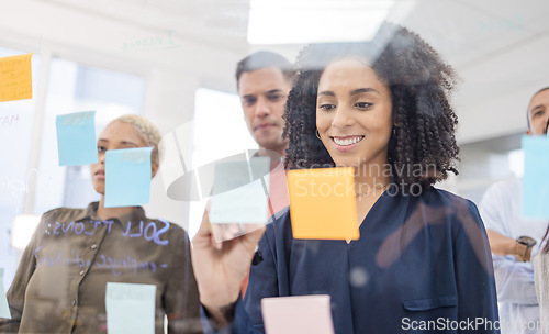 Image of Black woman, smile and writing schedule in planning, strategy or brainstorming on glass wall at office. African American female designer in teamwork project plan, tasks or post it with sticky note