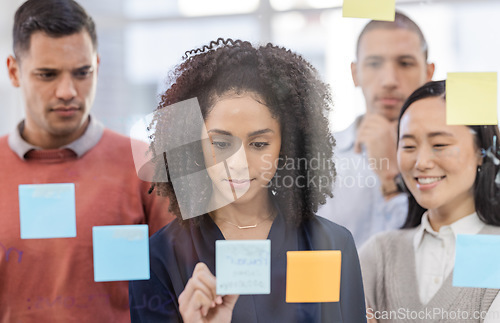 Image of Black woman, writing and schedule planning for strategy or team brainstorming on glass wall at office. African American female designer in teamwork project plan, tasks or post it with sticky note