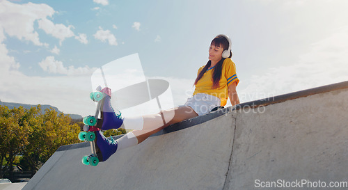 Image of Peace, music and rollerblades with woman in skate park for summer break, streaming and sports. Fitness, relax and skating with girl listening to headphones in outdoors for hobby, freedom and health