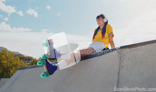 Image of Relax, music and rollerblades with woman in skate park for summer break, streaming and sports. Fitness, peace and skating with girl listening to headphones in outdoors for hobby, freedom and peace