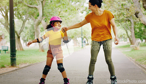 Image of Mother, park and holding hands to rollerskate with girl child with care, learning and support. Interracial parent, teaching and woman with kid, smile and helping hand on road for skating on holiday