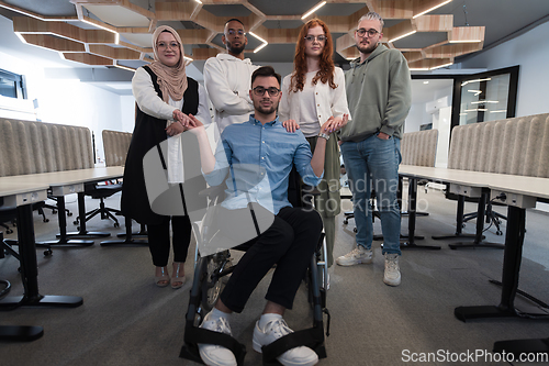 Image of Young businessmen in a modern office extend a handshake to their business colleague in a wheelchair, showcasing inclusivity, support, and unity in the corporate environment.