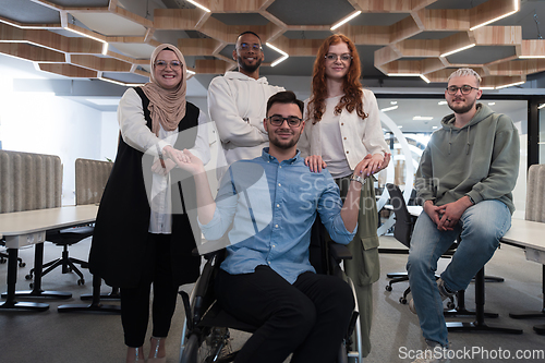 Image of Young businessmen in a modern office extend a handshake to their business colleague in a wheelchair, showcasing inclusivity, support, and unity in the corporate environment.