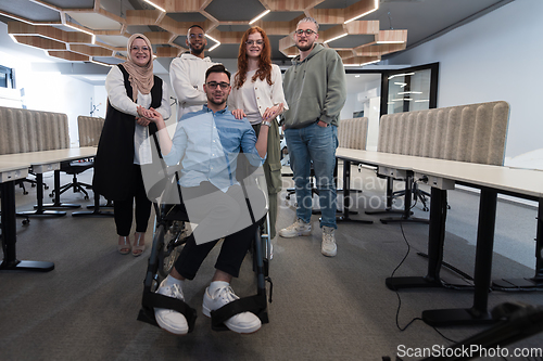 Image of Young businessmen in a modern office extend a handshake to their business colleague in a wheelchair, showcasing inclusivity, support, and unity in the corporate environment.