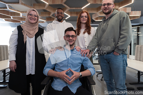 Image of Young businessmen in a modern office extend a handshake to their business colleague in a wheelchair, showcasing inclusivity, support, and unity in the corporate environment.
