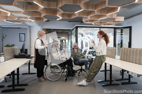 Image of Young group of business people brainstorming together in a startup space, discussing business projects, investments, and solving challenges.