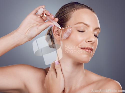 Image of Woman, face roller and beauty of facial product of aesthetic skincare massage in studio. Female model, rose quartz treatment and wellness for natural cosmetics, crystal stone dermatology or salon spa