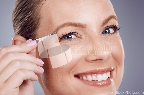 Image of Eyebrows, cosmetic and portrait of a woman with a tweezers isolated on a grey studio background. Beauty, treatment and happy model plucking hair from face for shaping and grooming on a backdrop
