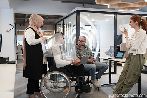 Image of Young group of business people brainstorming together in a startup space, discussing business projects, investments, and solving challenges.