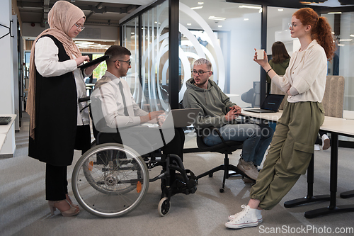 Image of Young group of business people brainstorming together in a startup space, discussing business projects, investments, and solving challenges.