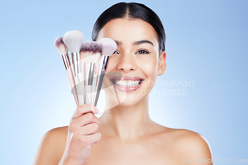 Image of Beauty brushes, makeup and portrait of woman with smile on blue background for cosmetics, powder and foundation. Skincare, cosmetology and face of girl with brush for application, eyeshadow and salon