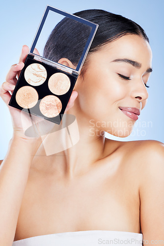 Image of Beauty, makeup and woman with palette and smile on blue background for cosmetics, powder and foundation. Skincare, spa aesthetic and face of girl with cosmetology highlighter, product and facial glow