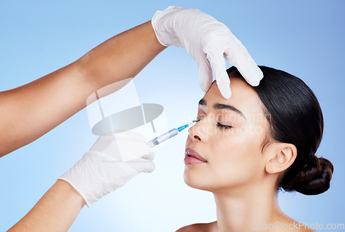 Image of Plastic surgery, face and surgeon injection for beauty, filler and change for a woman in studio. Aesthetic model and doctor hands for cosmetic surgery, transformation or dermatology blue background