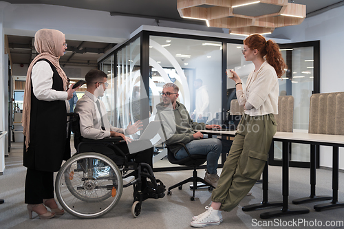 Image of Young group of business people brainstorming together in a startup space, discussing business projects, investments, and solving challenges.