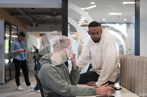 Image of Young group of business people brainstorming together in a startup space, discussing business projects, investments, and solving challenges.