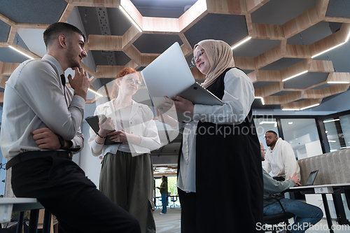 Image of Young group of business people brainstorming together in a startup space, discussing business projects, investments, and solving challenges.