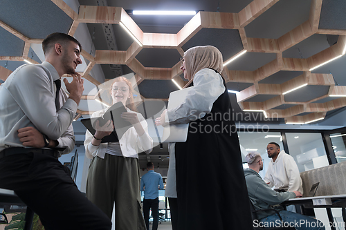 Image of Young group of business people brainstorming together in a startup space, discussing business projects, investments, and solving challenges.