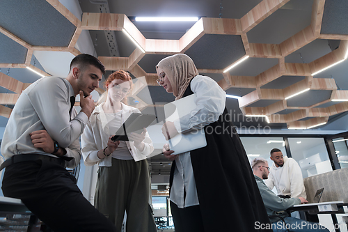 Image of Young group of business people brainstorming together in a startup space, discussing business projects, investments, and solving challenges.