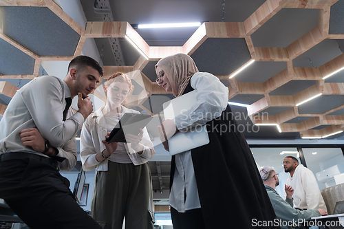 Image of Young group of business people brainstorming together in a startup space, discussing business projects, investments, and solving challenges.