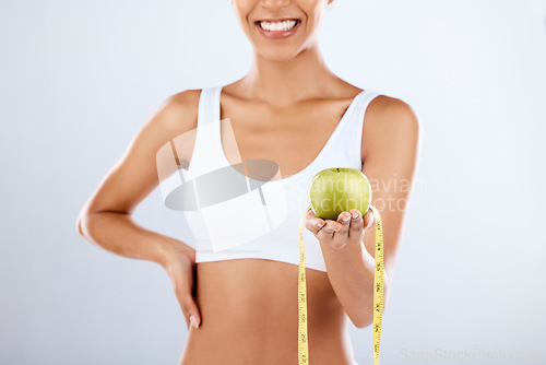 Image of Detox, apple and tape measure with a fitness black woman in studio on a gray background for healthy eating. Exercise, fruit and wellness with a female posing to promote a lifestyle of health or diet