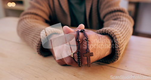 Image of Hands, rosary and cross with closeup for faith, peace and hope at desk, home or praying for worship. Person, crucifix and jewelry for religion, mindfulness and connection to holy spirit, Jesus or God