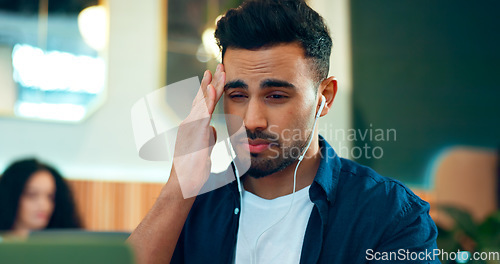 Image of Man, headache and pain at cafe for online research, planning and remote work stress, deadline or mistake. Frustrated freelancer listening to music with migraine, mental health and tired in restaurant