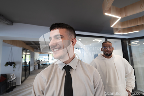 Image of A group of young business professionals stands together, taking a well-deserved break from their busy workday, showcasing camaraderie, teamwork, and a moment of relaxation in their dynamic workplace