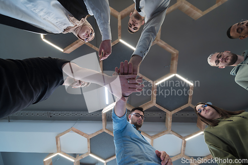 Image of A group of young businessmen offer their hands together, symbolizing togetherness in the business world