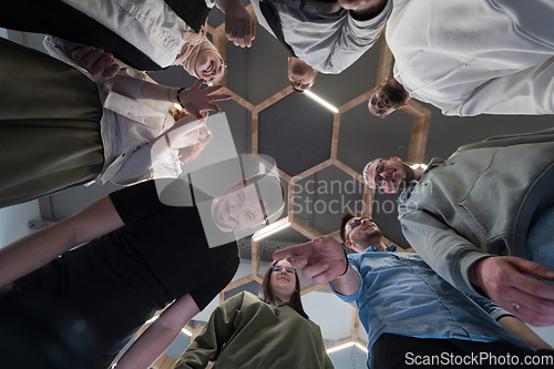 Image of In a modern office, a group of young business professionals is captured in a warm and embracing hug, reflecting the spirit of unity, collaboration, and shared success in their dynamic workplace.