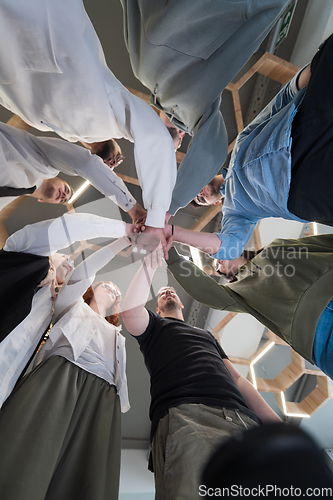 Image of A group of young businessmen offer their hands together, symbolizing togetherness in the business world