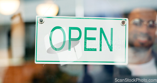 Image of Storefront, small business or open sign on window in coffee shop or restaurant for service or advertising. Man, portrait or entrepreneur holding board, poster or welcome for message in cafe or diner