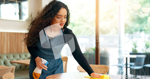 Image of Waitress, woman and cleaning table in restaurant for dust, bacteria and dirt with cloth, spray or detergent. Barista, person and wipe wooden furniture in coffee shop or cafe with chemical liquid