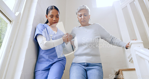Image of Woman, nurse and helping senior on stairs in retirement home for support, trust or healthcare. Female person, medical caregiver holding hands with retired or mature patient down a staircase at house
