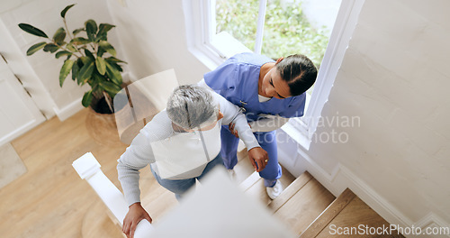 Image of Woman, nurse and helping senior up stairs in retirement home for support, trust or healthcare. Female person, medical caregiver holding arms on staircase above with retired or mature patient at house