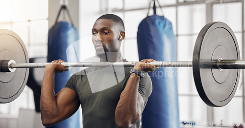 Image of Earphones, barbell and black man training in gym while listening to music, radio or podcast. Energy, health and male bodybuilder from South Africa weight lifting while streaming audio or sound track.