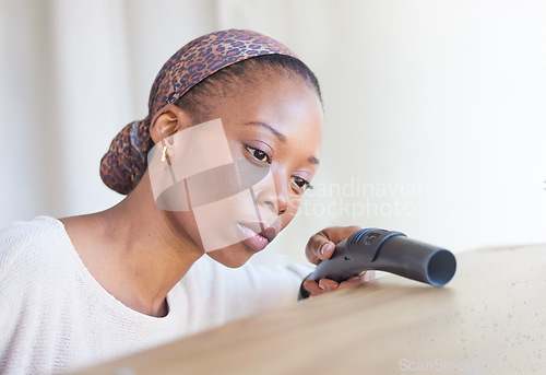 Image of Cleaning, vacuum and hygiene with a black woman doing housework or chores alone in a home. Living room, furniture and housekeeping with a female cleaner working in a house on domestic duties