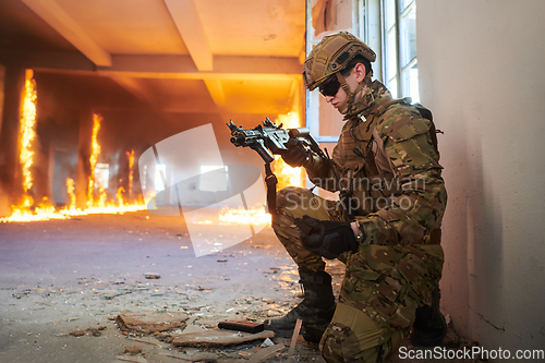 Image of Soldier in action near window changing magazine and take cover